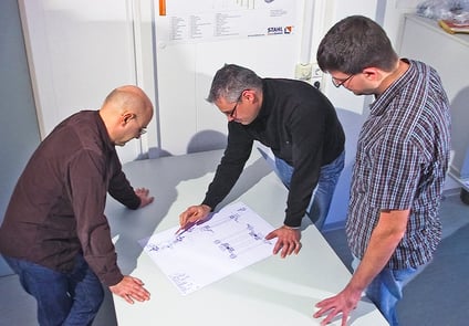 Image of three men looking at paperwork