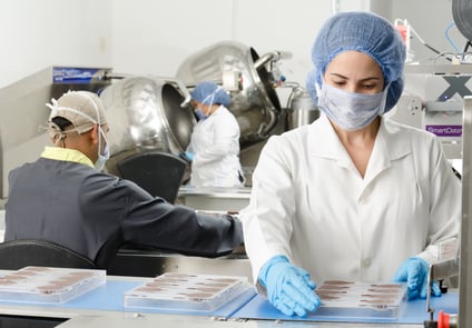 Image of Three People working in a lab with Gloves, Hair Nets, and Masks on