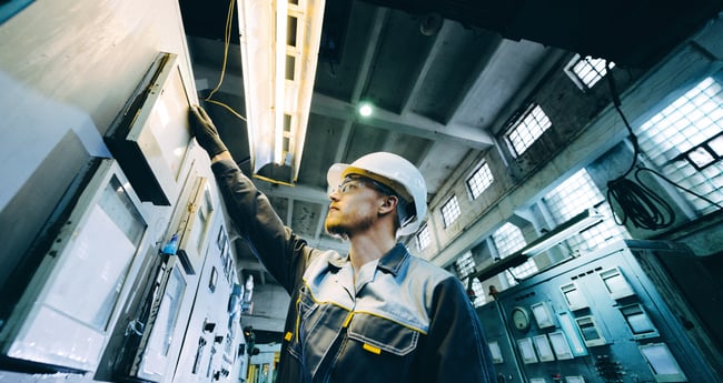 Image of man in hard hat and safety goggles working on technical system