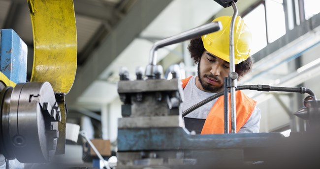 Young manual worker working on machinery