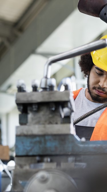 Young manual worker working on machinery