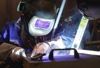 Mitarbeiter in er eigenen Hubtisch-Fertigung von COLUMBUS McKINNON schweißt gerade die Scherenkonstruktion eines Hubtischs.